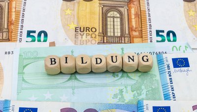 Buchstabenwürfen, die das Wort Bildung zeigen, liegen auf unterschiedlichen Geldscheinen